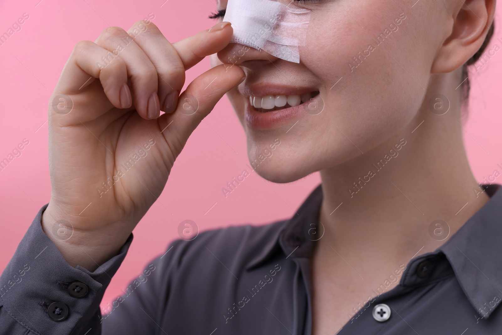 Photo of Woman with medical bandage on her nose after plastic surgery operation against background, closeup