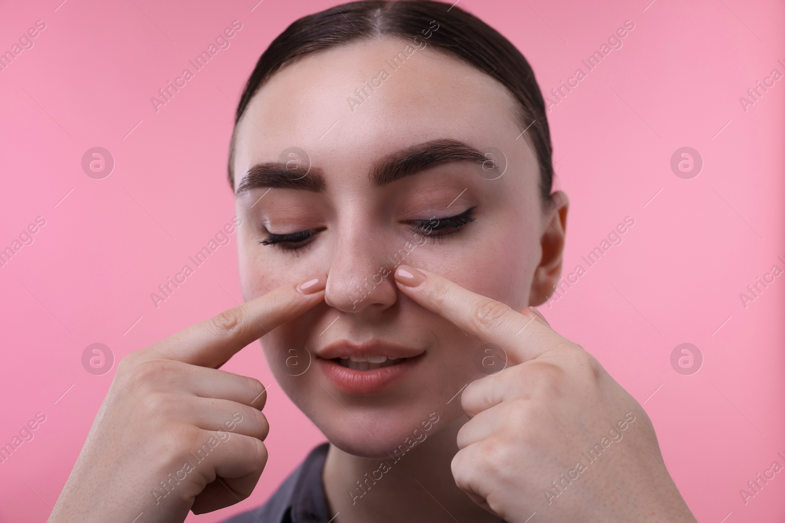 Photo of Woman touching her nose on pink background