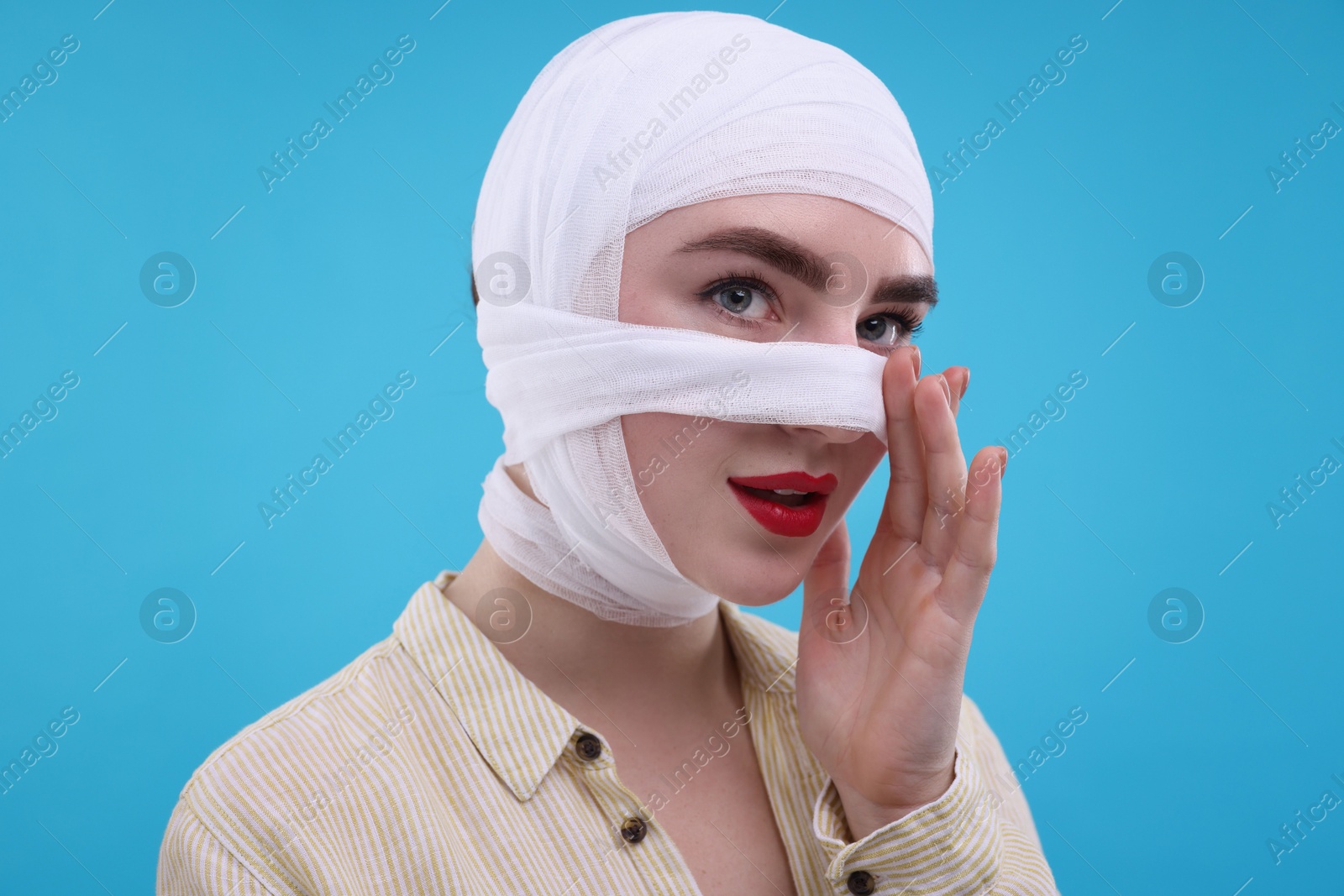 Photo of Woman with nose wrapped in medical bandage after plastic surgery operation on light blue background