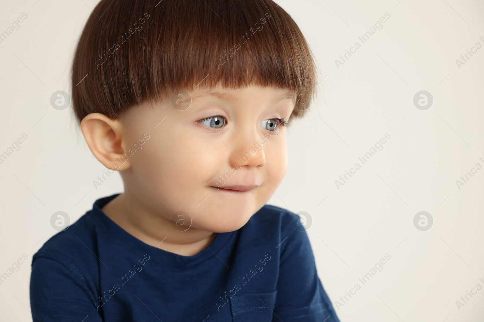 Photo of Portrait of cute little boy on light grey background. Space for text