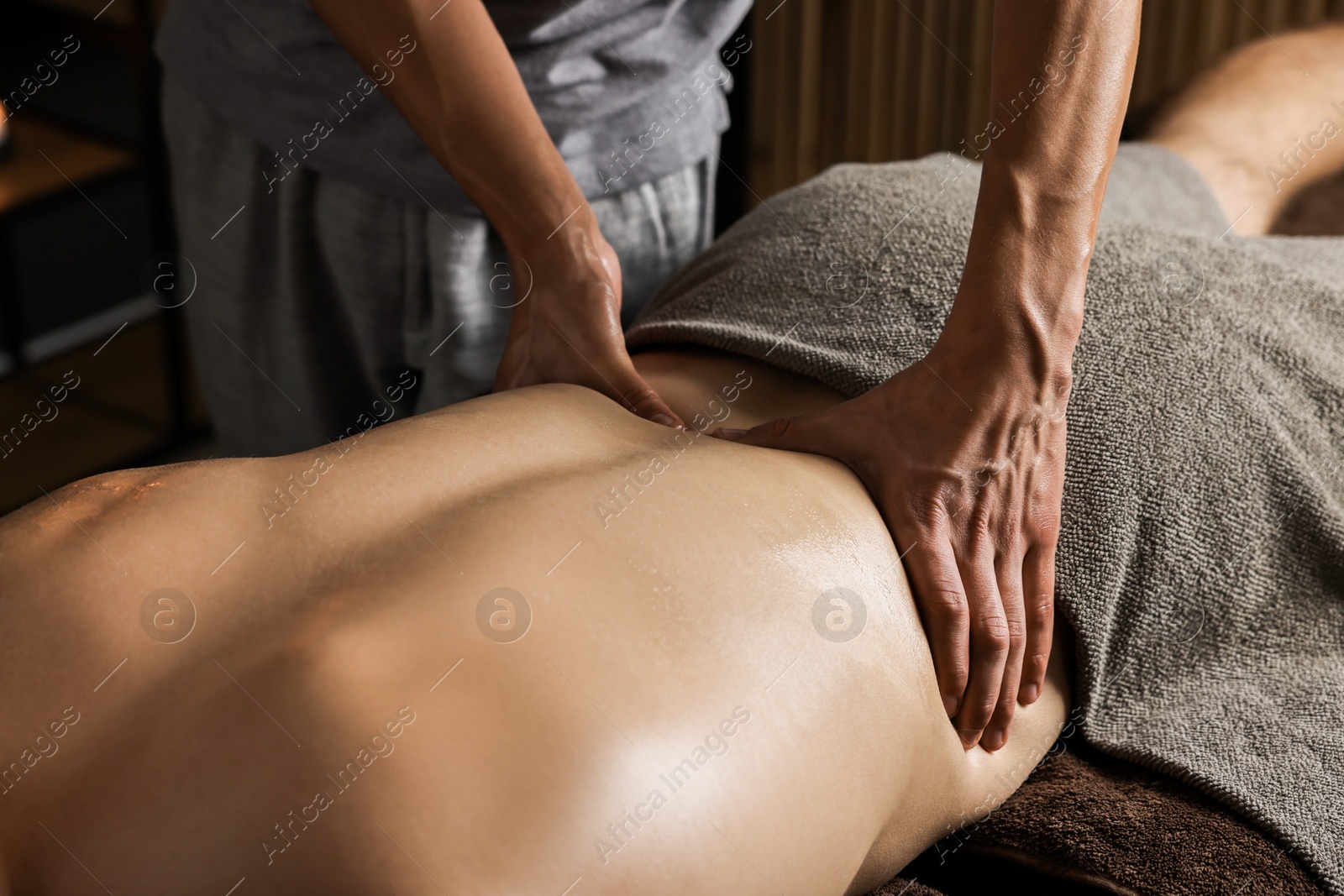 Photo of Professional physiotherapist doing back massage for his client indoors, closeup