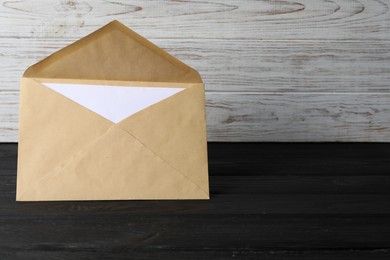 Kraft paper envelope with letter on black wooden table. Mockup for design