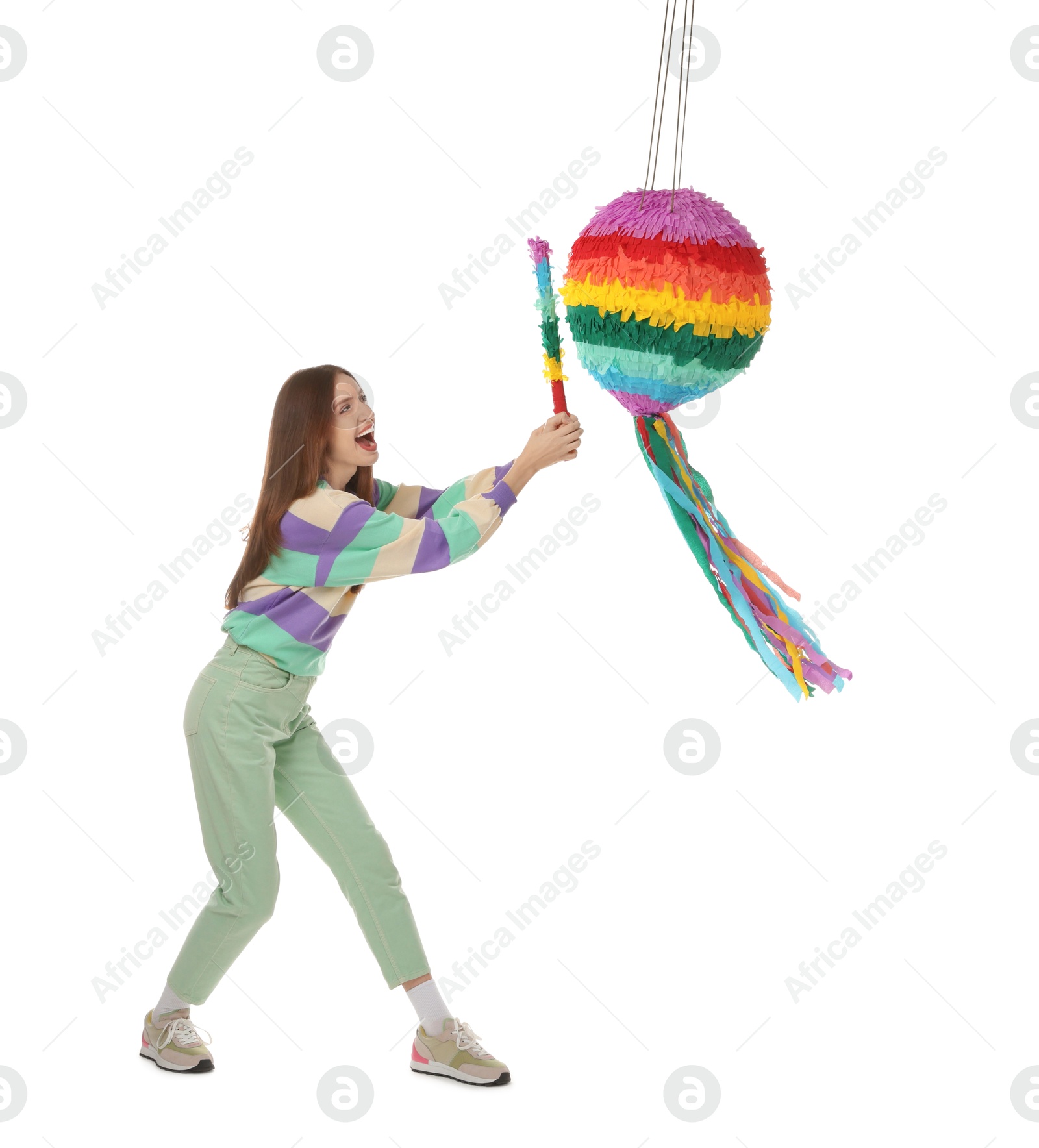 Photo of Emotional woman breaking colorful pinata with stick on white background