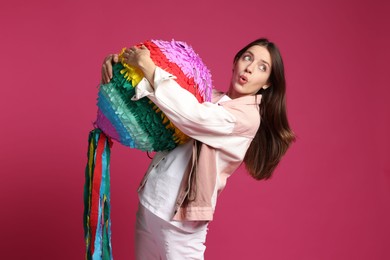 Photo of Emotional woman with colorful pinata on pink background