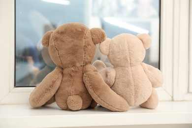 Photo of Teddy bears on window sill at home, back view