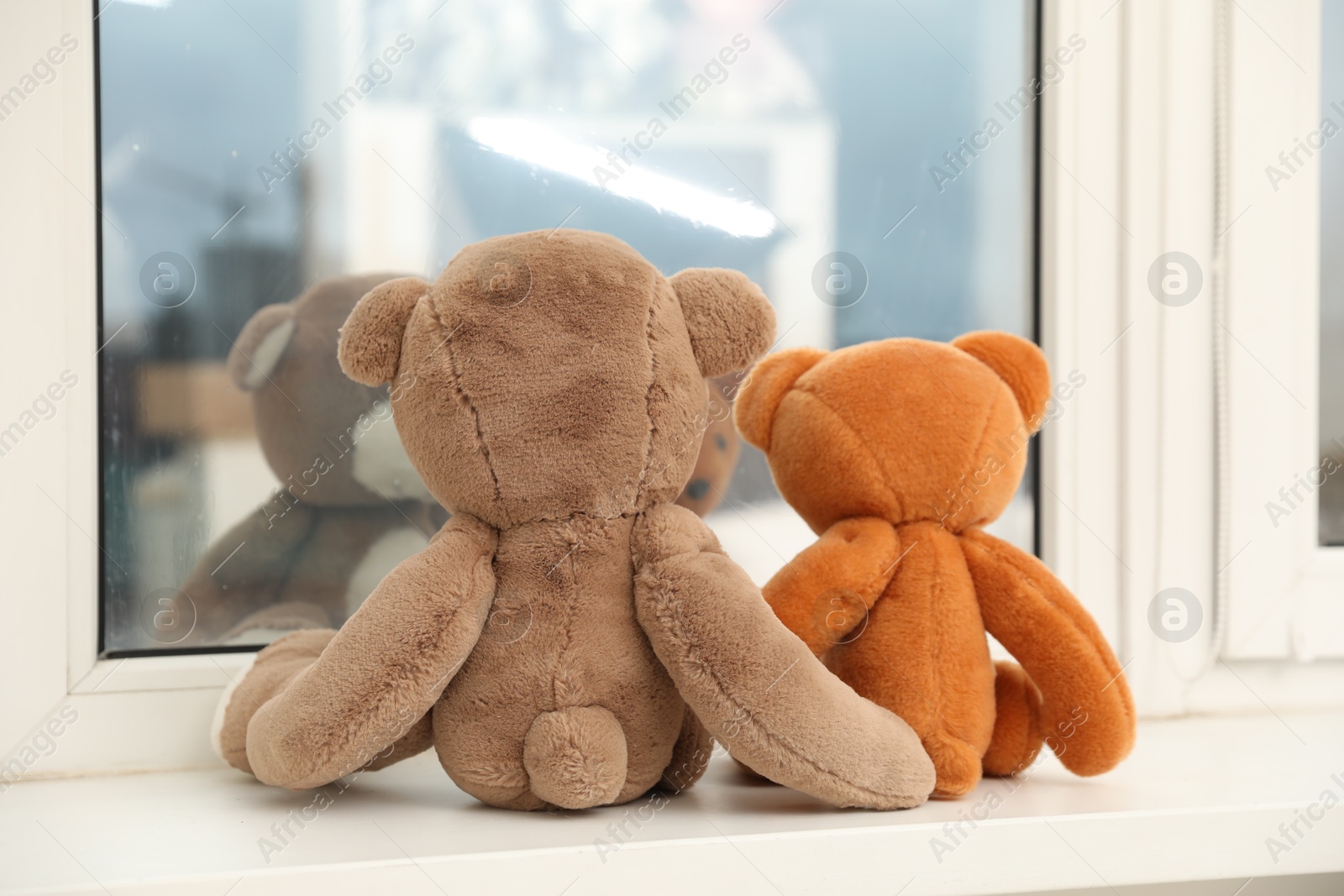 Photo of Teddy bears on window sill at home, back view