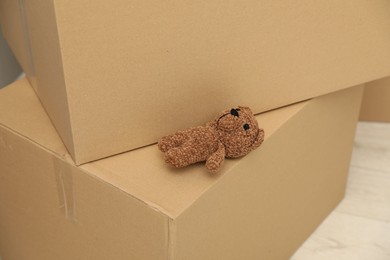 Photo of Knitted toy bear left on boxes at home