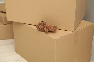 Photo of Knitted toy bear left on boxes at home