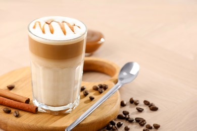 Photo of Tasty latte macchiato in glass on wooden table, closeup. Space for text