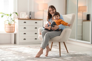 Photo of Happy mother with her little son sitting on armchair at home. Space for text