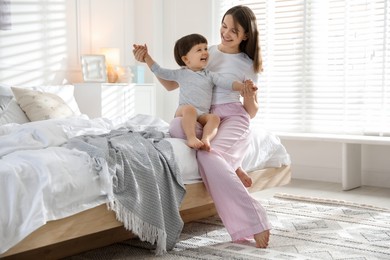 Photo of Happy mother playing with her little son in bedroom