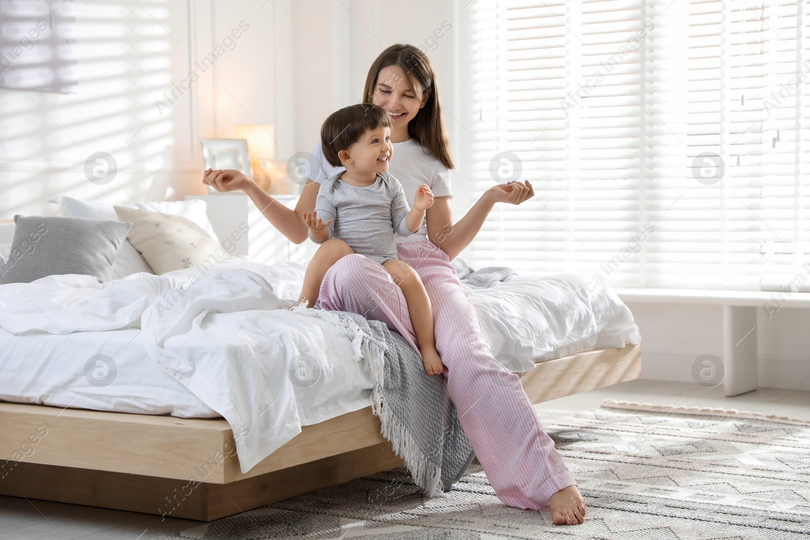 Photo of Happy mother playing with her little son in bedroom