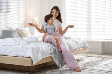 Photo of Happy mother playing with her little son in bedroom