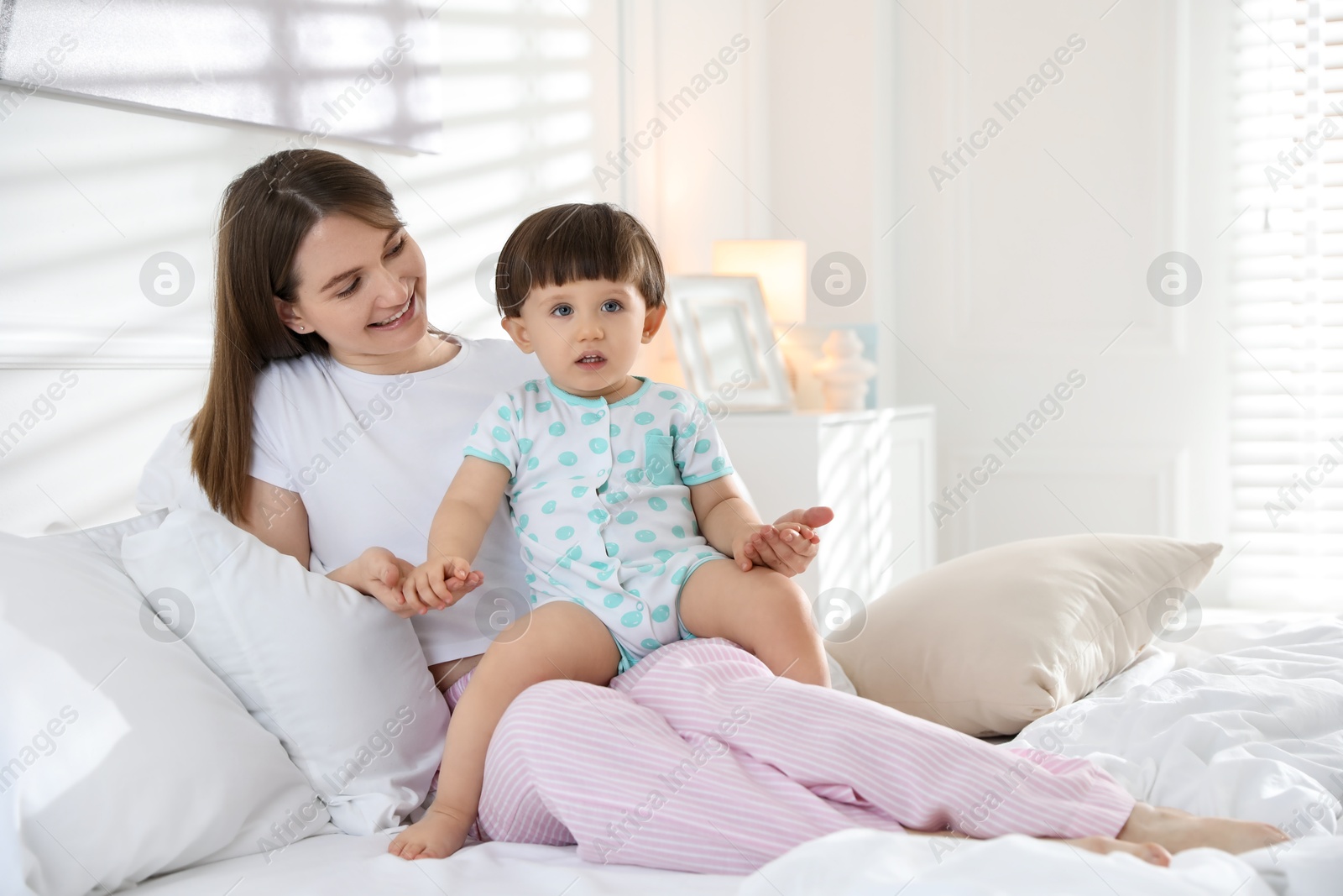 Photo of Happy mother with her little son on bed at home