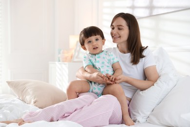 Photo of Happy mother with her little son on bed at home