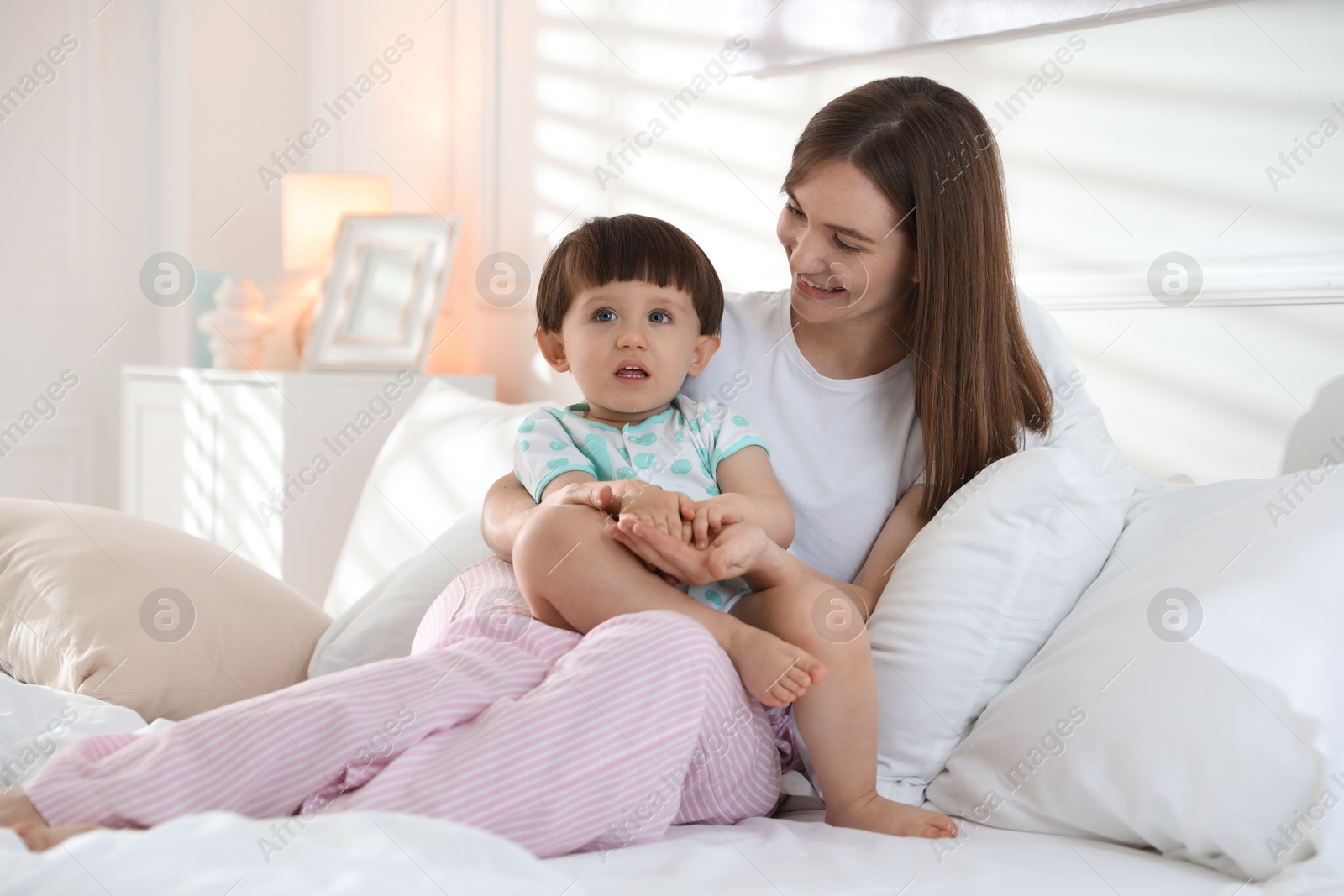 Photo of Happy mother with her little son on bed at home