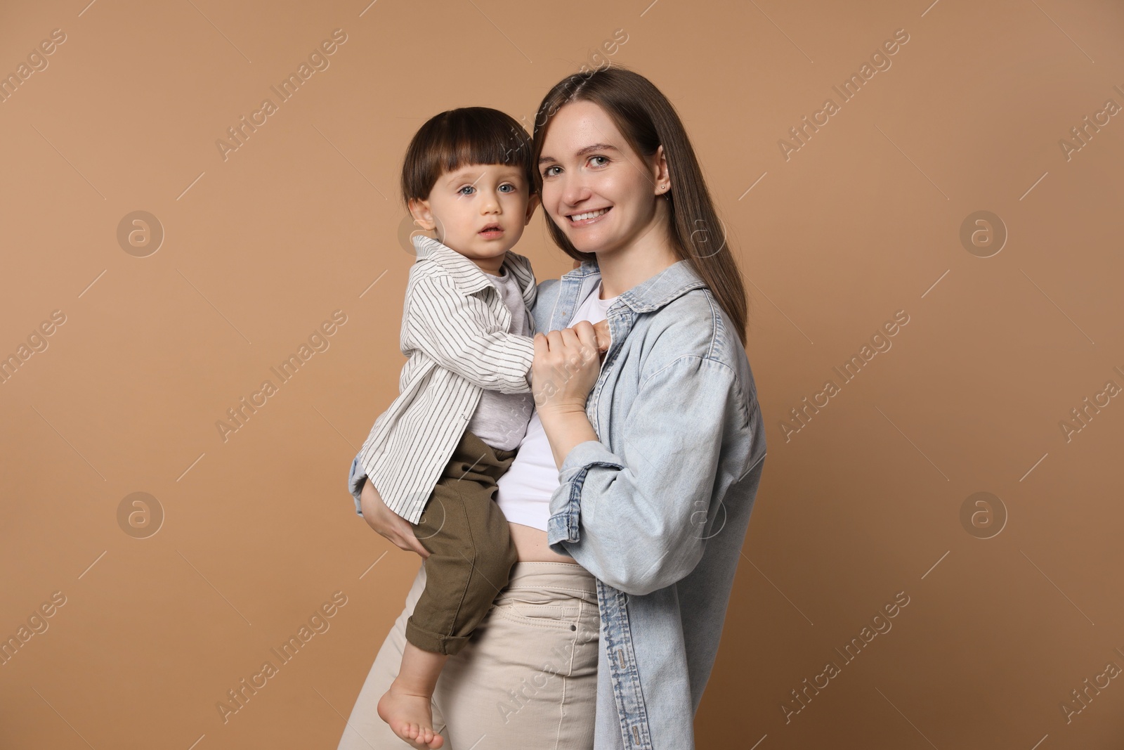 Photo of Family portrait of happy mother with her little son on beige background