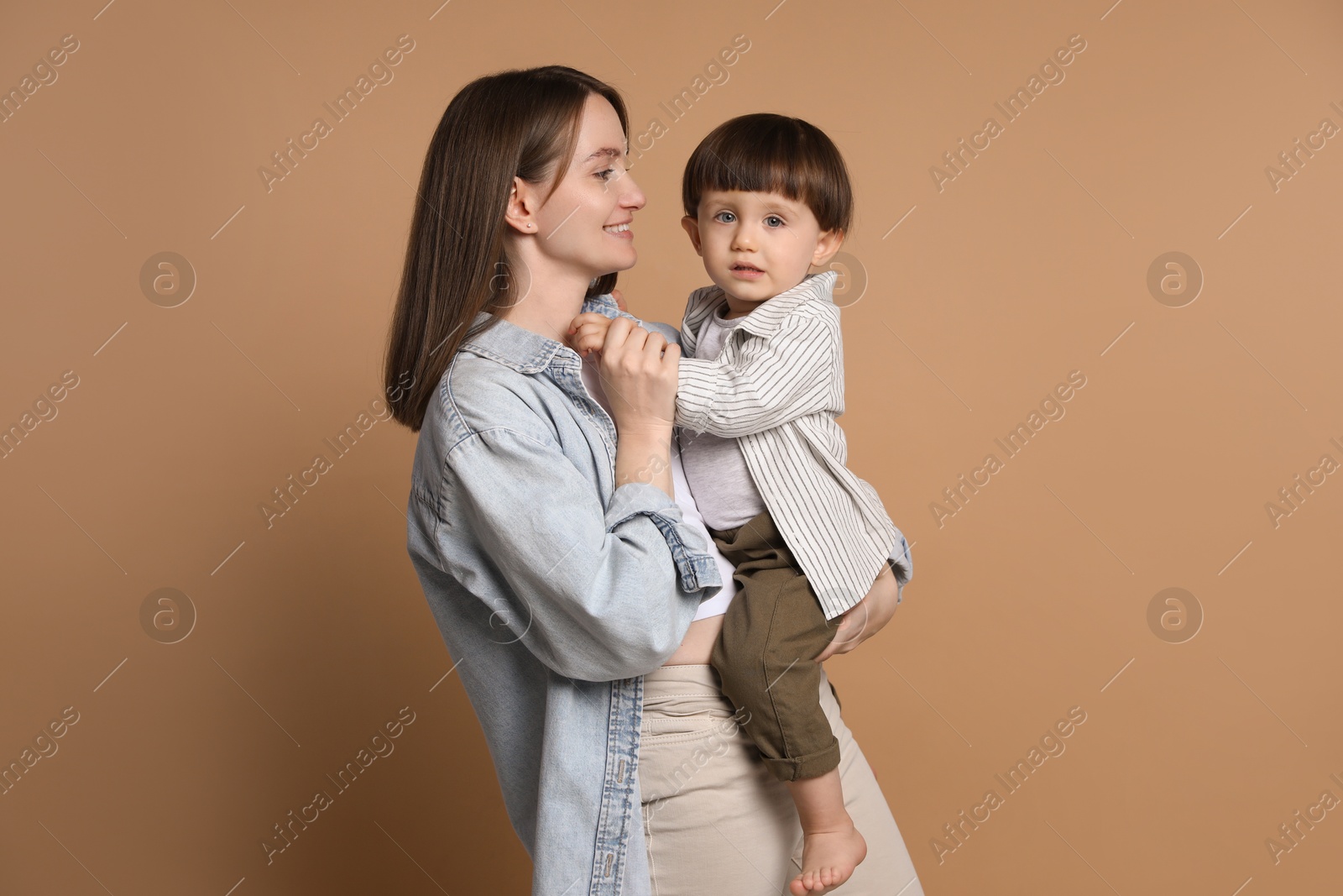 Photo of Family portrait of happy mother with her little son on beige background