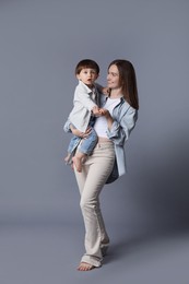 Photo of Happy mother with her little son on grey background