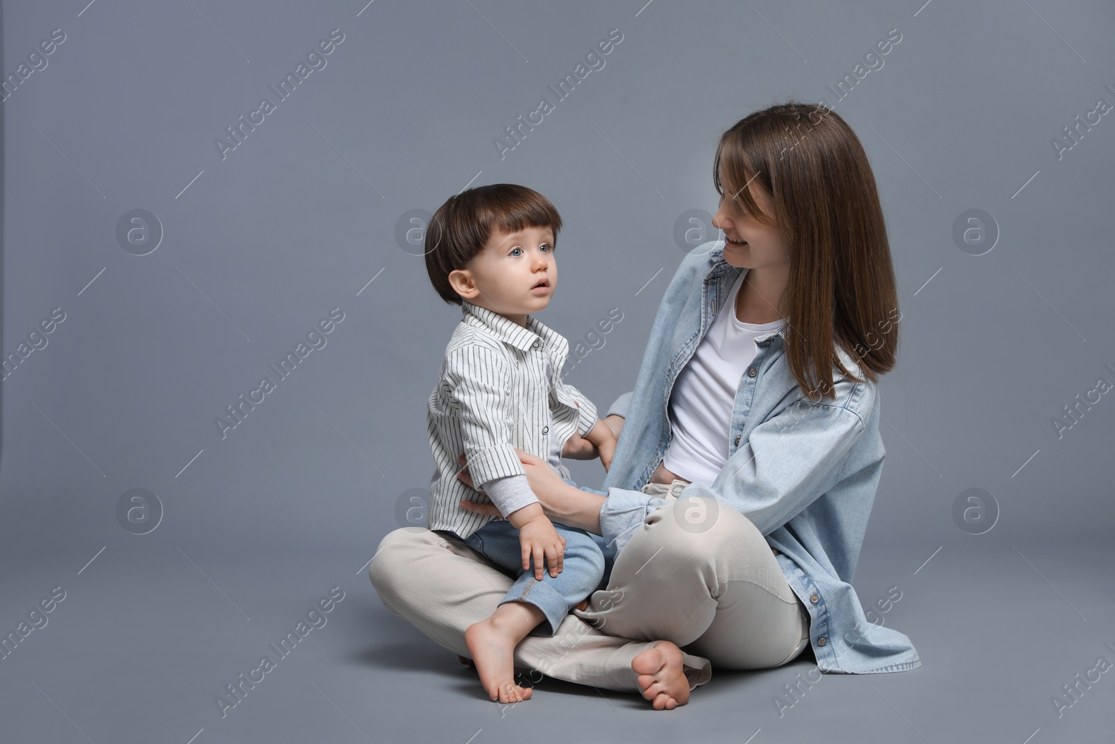 Photo of Happy mother with her little son on grey background