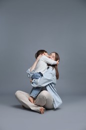 Photo of Mother hugging her little son on grey background