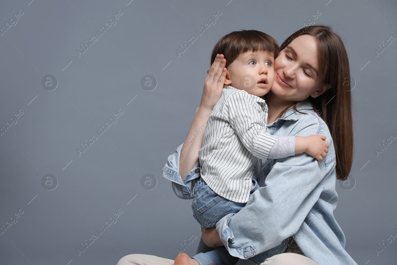 Photo of Mother hugging her little son on grey background. Space for text