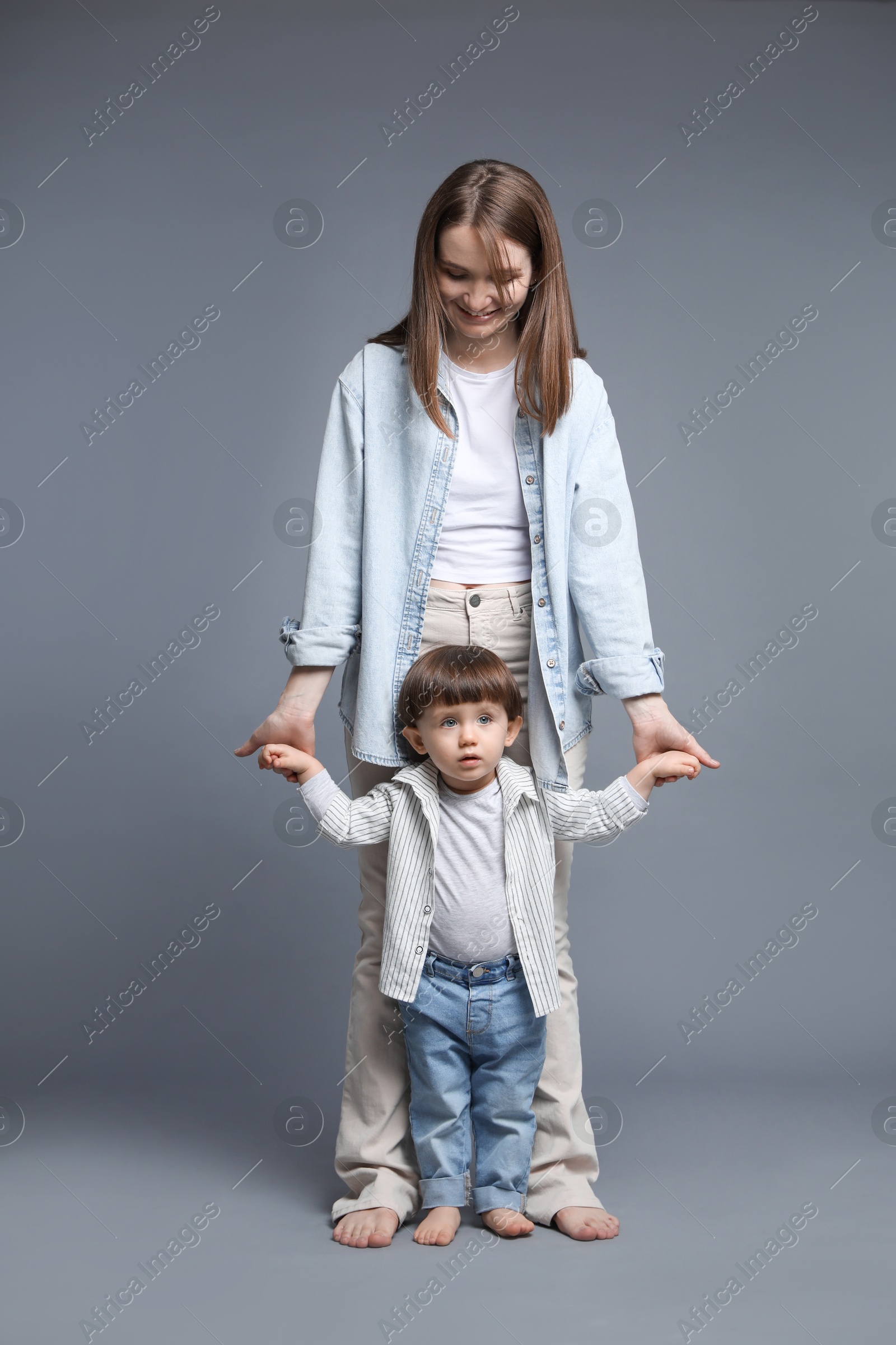 Photo of Happy mother with her little son on grey background