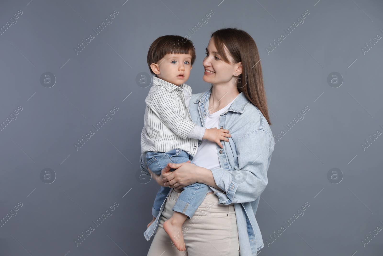 Photo of Happy mother with her little son on grey background