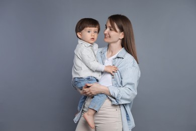 Happy mother with her little son on grey background