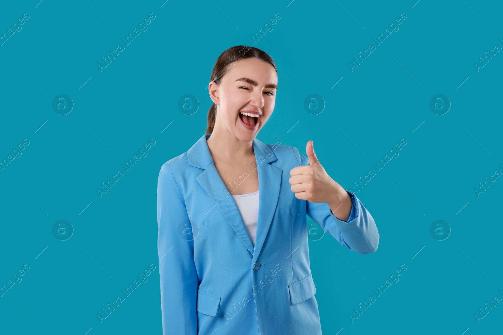 Photo of Happy woman showing thumbs up on light blue background. Like gesture