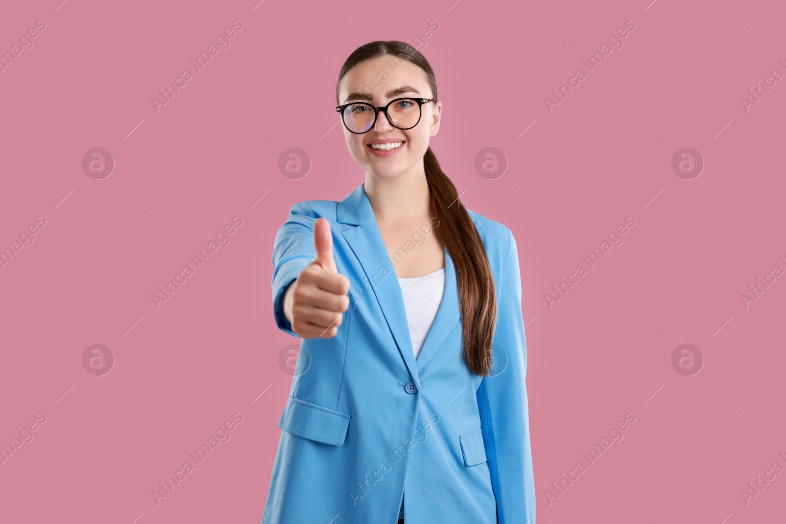 Photo of Happy woman showing thumbs up on pink background. Like gesture