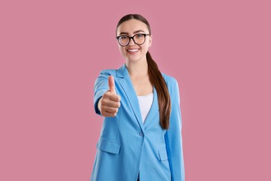 Photo of Happy woman showing thumbs up on pink background. Like gesture