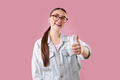 Photo of Happy woman showing thumbs up on pink background. Like gesture