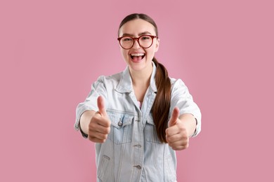 Photo of Happy woman showing thumbs up on pink background. Like gesture