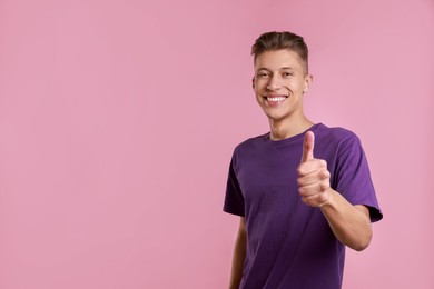 Photo of Happy man showing thumbs up on pink background, space for text. Like gesture