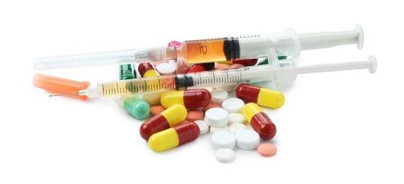 Photo of Drug addiction. Different pills and syringes isolated on white