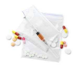 Photo of Drug addiction. Different pills, plastic bags with powder and syringe isolated on white, top view