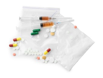 Photo of Drug addiction. Different pills, plastic bags with powder and syringes isolated on white, top view