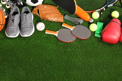 Photo of Different sport equipment on artificial grass, above view. Space for text