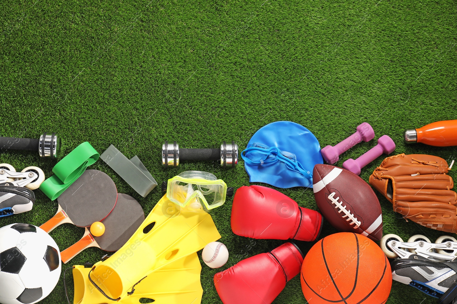 Photo of Different sport equipment on artificial grass, flat lay. Space for text