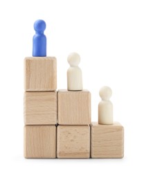 Photo of Human figures on wooden blocks, blue one on top against white background. Competition concept