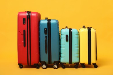 Photo of Many closed colorful suitcases on orange background