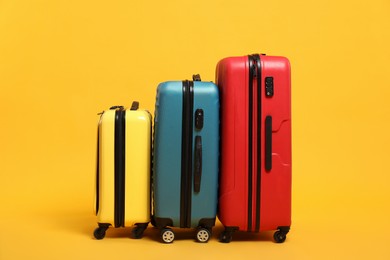 Photo of Many closed colorful suitcases on orange background