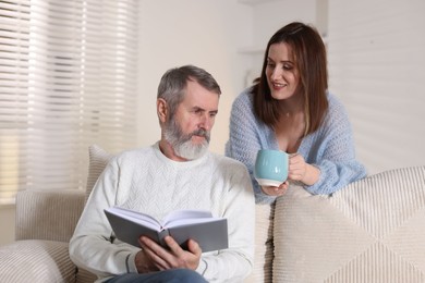 Photo of Happy adult daughter and her father spending time together at home