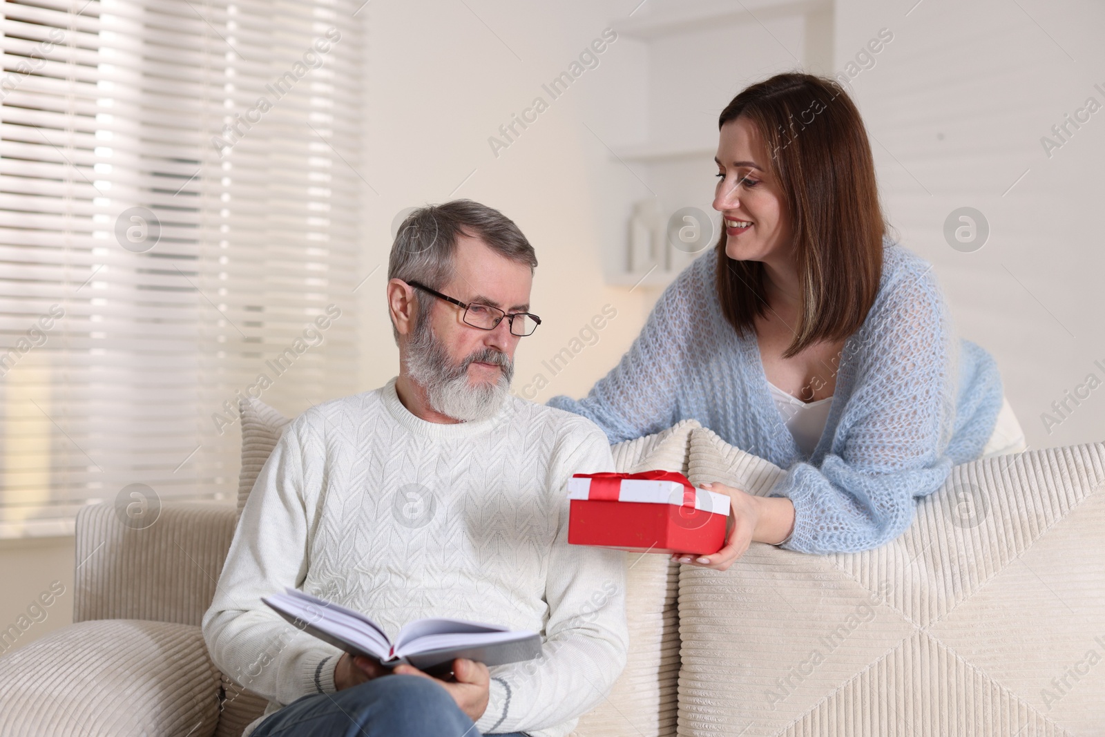 Photo of Happy daughter presenting her father with gift at home