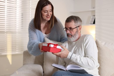 Photo of Happy daughter presenting her father with gift at home