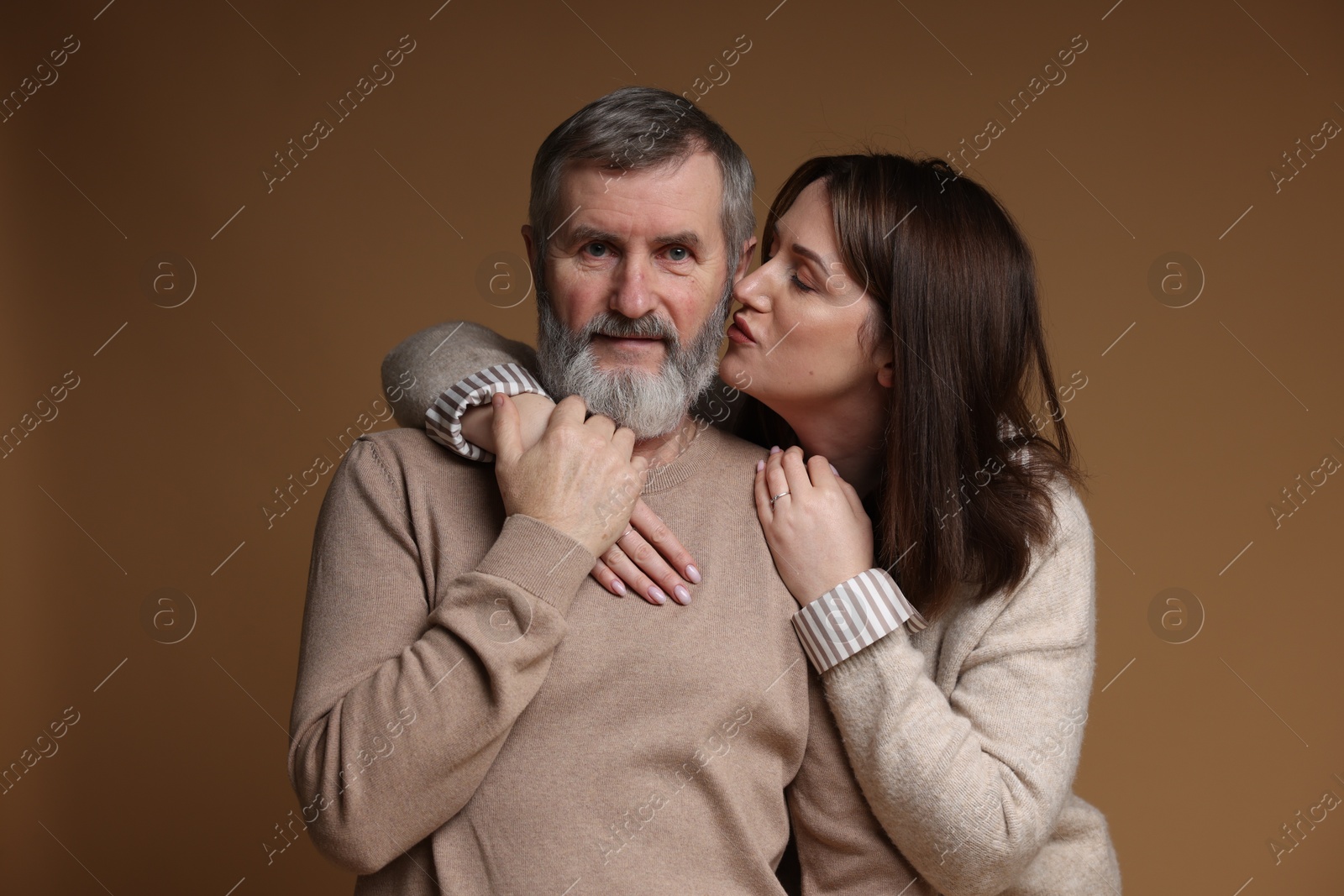 Photo of Daughter kissing her father on brown background