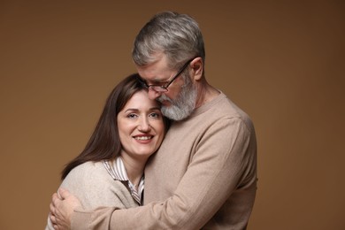 Photo of Father hugging his happy daughter on brown background