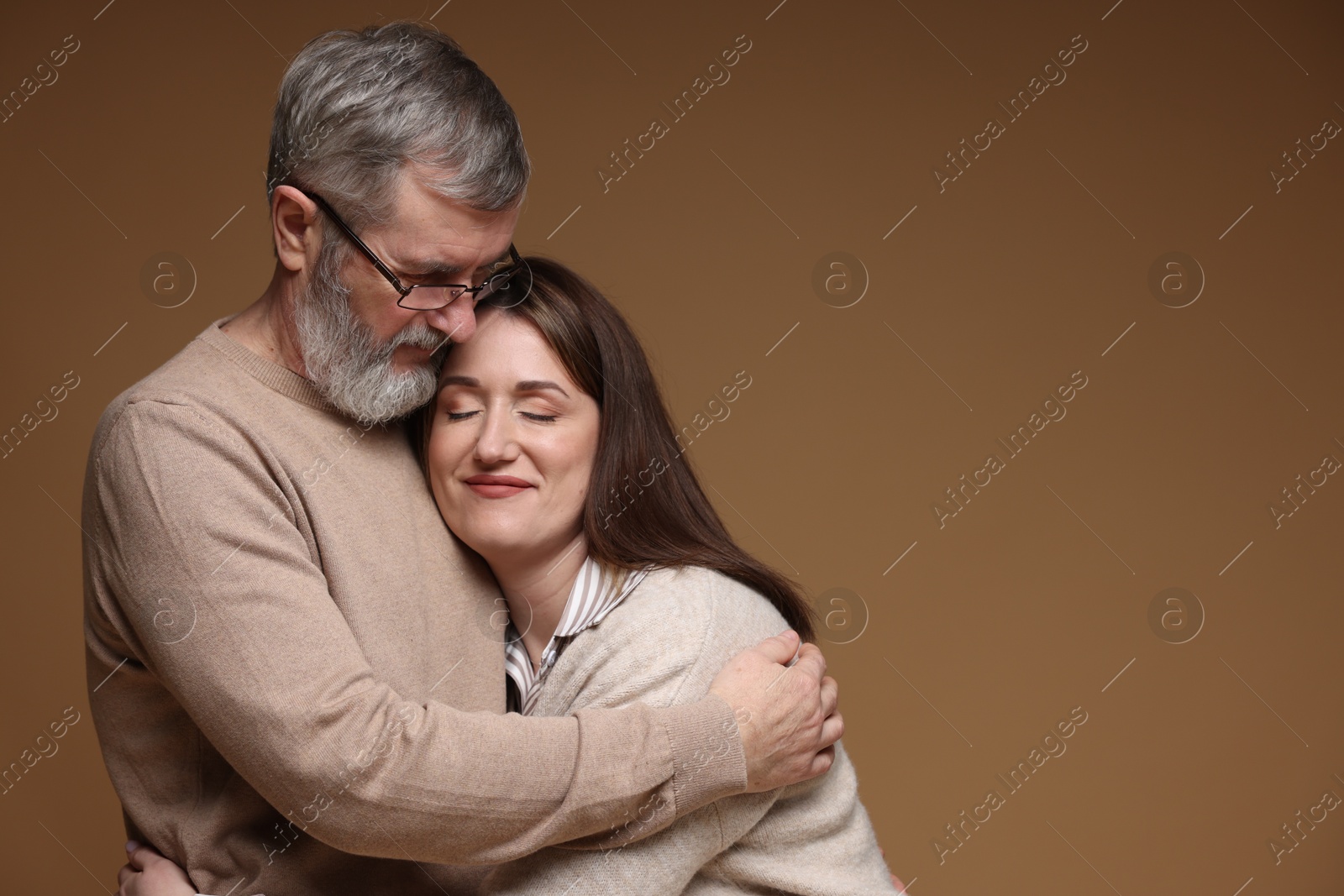 Photo of Father hugging his daughter on brown background, space for text