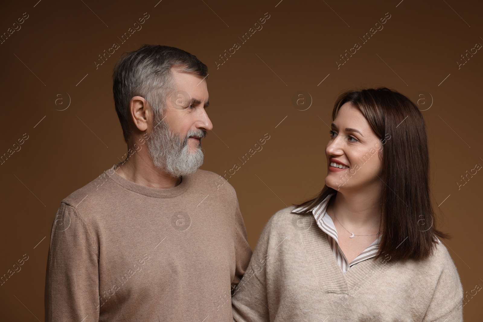 Photo of Happy daughter and her father looking at each other on brown background